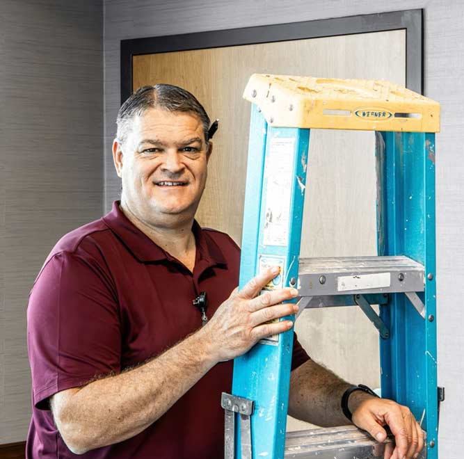 A man stands in Floyd Valley Hospital, Le Mars, IA, holding a ladder